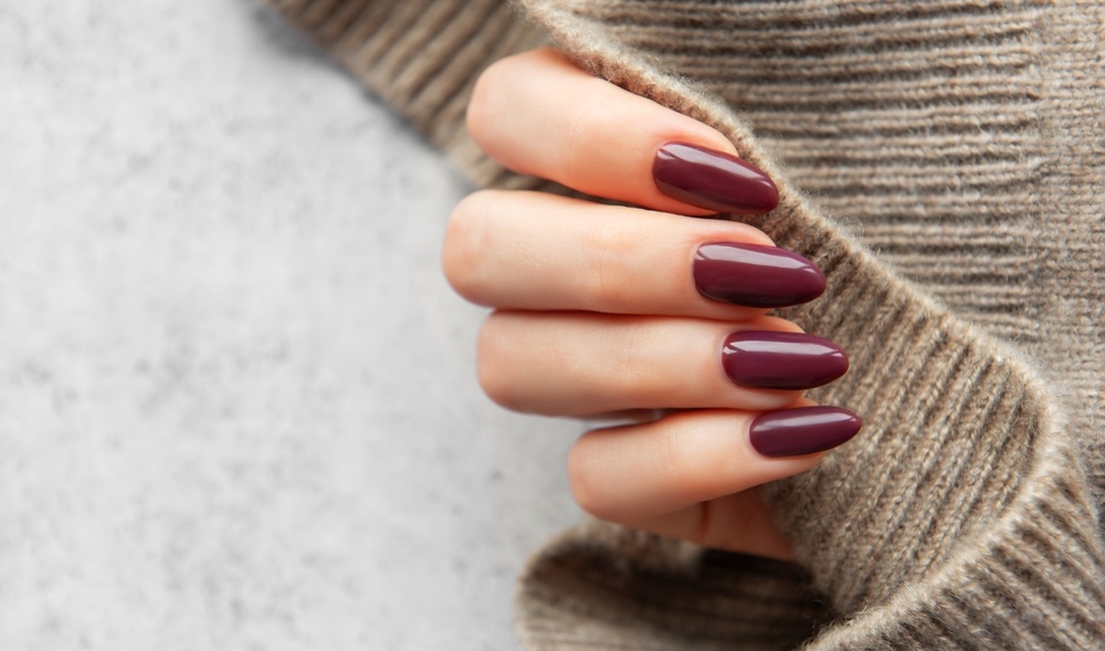 A,Well-manicured,Hand,Showcases,Dark,Burgundy,Nails,While,Holding,A vernikia-kai-imimonimo